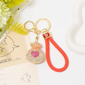 Detailed close-up of rhinestone heart money bag keychain with red leather braided strap.