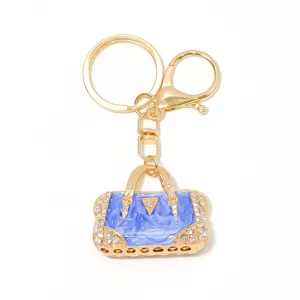 Detailansicht des luxuriösen goldenen Metallschlüsselanhängers mit eleganter blauer Tasche.