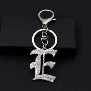 Close-up detail of the sparkling rhinestone Gothic letter E keychain, silver metal accessory.