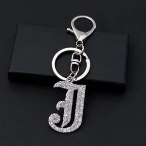 Close-up detail of silver metal rhinestone letter J keychain keyring accessory for bags.