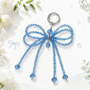 Sparkling blue crystal beaded bow bag charm detail with shiny silver clasp and dangling strands.