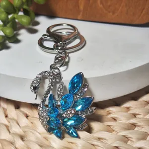 Rhinestone swan keychain detail shot, crystal bag charm sparkling accessory display.