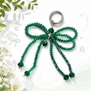 Detailed close-up view of the sparkling green crystal bow keychain and elegant bag charm.