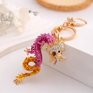 Detailed view of a sparkling rhinestone dragon keychain, stylish metal bag and car key ring.