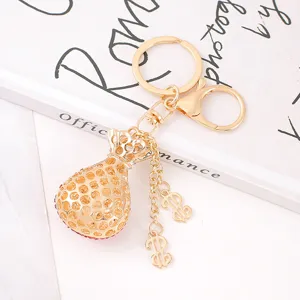 Gold rhinestone money bag keychain with dollar sign pendants, stylish metal bag charm for keys or bags.