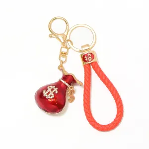 Vue détaillée du porte-clés bourse strass rouge avec une lanière en cuir tressé doré.