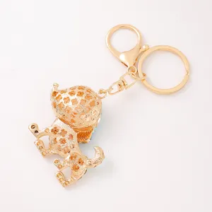 Detail view of the gold-tone metal puppy keychain with rhinestone and clover cutouts.