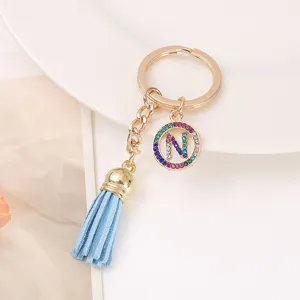 Detailed shot of a stylish gold-tone keychain with a blue tassel and a rhinestone letter N charm.