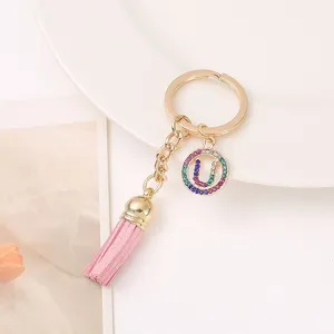 Close-up detail of keychain with pink tassel, gold chain and rhinestone U letter pendant.