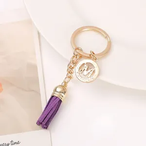Gold metal keychain with purple tassel and letter M charm, stylish bag pendant accessory.