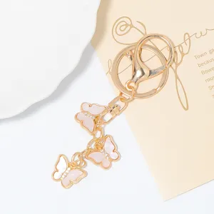 Close-up detail of luxury gold keychain with pink butterfly charms and sparkling rhinestones.