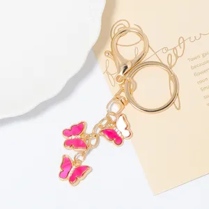 Gold metal butterfly keychain with pink enamel and sparkling rhinestones, elegant bag charm detail.