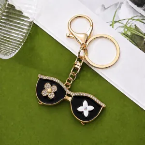 Detailed view of the luxury sunglasses keychain featuring sparkling rhinestones and gold chain.