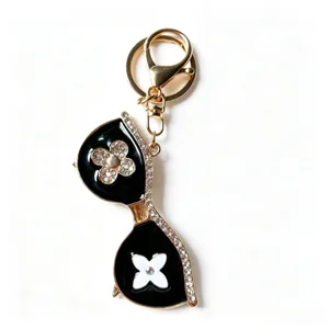 Chic sunglasses shape metal keychain with sparkling rhinestones and elegant clover pendant.