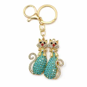 Dettaglio portachiavi gatto gemello in strass scintillanti, accessorio borsa dorato.