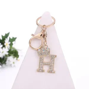 Close-up view of gold rhinestone letter H crown keychain charm with sparkly crystals and clasp.