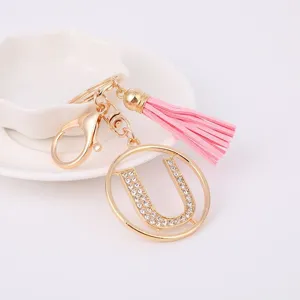 Gold rhinestone letter U keychain with pink tassel charm, detailed metal bag accessory.