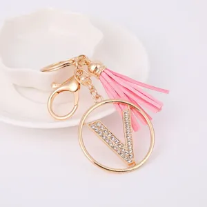 Metal rhinestone letter V keychain with pink tassel charm, elegant bag accessory detail view.