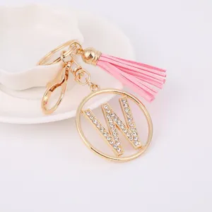 Gold metal rhinestone letter W keychain with pink tassel pendant for bag details view.