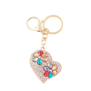 Close-up van hartvormige strass-sleutelhanger met kristallen bloemen en gouden sluiting.