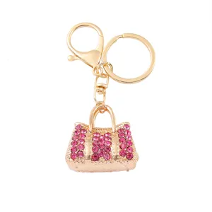 Vue détaillée d'un porte-clés en métal doré avec un charm de sac à main strass rose scintillant.