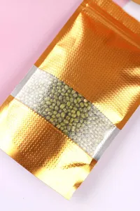 Detailansicht goldener geprägter Aluminiumfolienbeutel mit Sichtfenster für Lebensmittel.