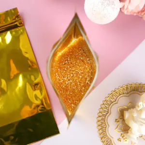 Draufsicht-Detail eines goldenen Standbeutels aus Aluminiumfolie gefüllt mit orangem Granulat