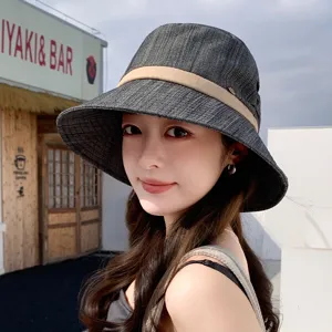 Detailed close-up view of the stylish dark grey bucket hat worn by a model outdoors.