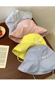 Dettaglio cappello da pescatore a righe con tessuto morbido, design elegante e vestibilità.