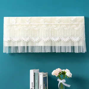 Dettaglio della copertura antipolvere per condizionatore in pizzo beige con ricamo floreale.