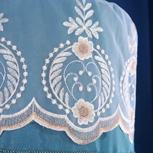 Primo piano della copertura per condizionatore blu con elegante ricamo floreale bianco e oro.