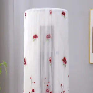 Detail view of white mesh cylindrical air conditioner dust cover with red floral embroidery.