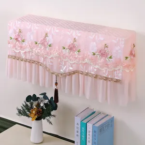 Dettaglio copertura per condizionatore in pizzo rosa, ricamo floreale e nappa decorativa.