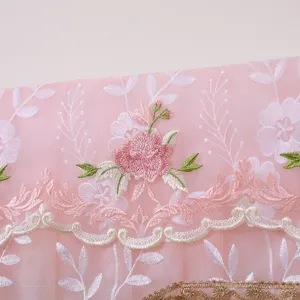 Primo piano della copertura per condizionatore in rete rosa con elegante ricamo floreale.