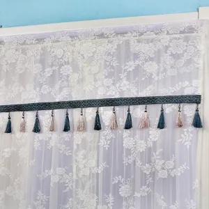 Lace curtain detail with decorative tassel trim, elegant sheer window panel design.
