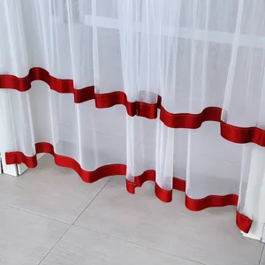 Close-up of white sheer curtain with vibrant red ribbon trim showing delicate stitching detail.