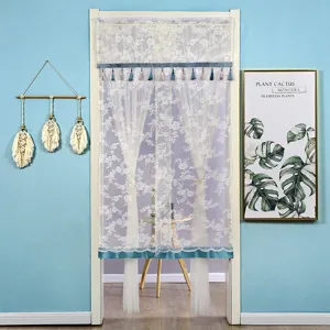 Detailed view of white floral lace door curtain with blue tassel hem for home decor.
