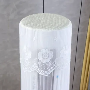 Closeup of a white cylindrical vertical air conditioner cover with delicate floral lace embroidery.