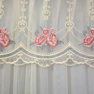 Detailed view of exquisite pink rose embroidery on cream white sheer lace curtain fabric.