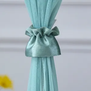 Close-up detail of sheer mesh curtain tie-back, elegant pleated fabric design for home decor.