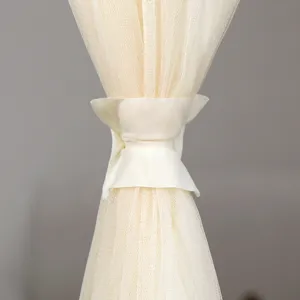 Close up detail of a cream sheer curtain with a matching tie back, elegant mesh fabric texture.