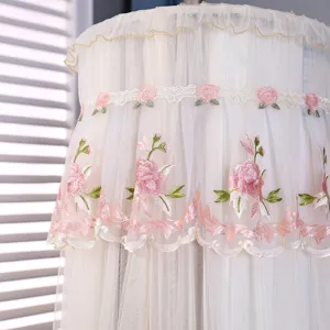 Primo piano della copertura antipolvere per condizionatore beige con ricamo di rose e volants.