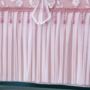 Dettaglio copritivv in pizzo rosa, elegante motivo floreale ricamato e graziosa frangia di perle.