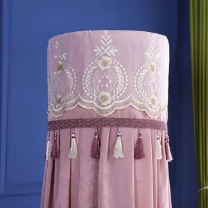 Dettaglio di copricondizionatore verticale rosa con ricamo nordico e nappe decorative.