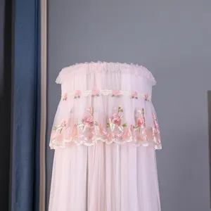 Fodera antipolvere verticale cilindrica in pizzo rosa con ricamo floreale e volant eleganti.