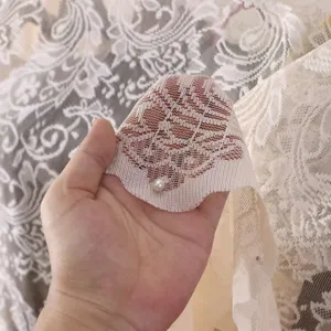 Exquisites beige Spitzen Staubschutz Detail mit feinem Blumenmuster und Perle verziert.
