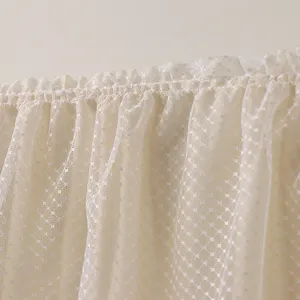 Gros plan sur le tissu de housse anti-poussière de climatiseur en dentelle beige et volants.