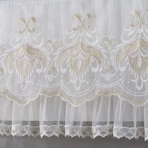 Detailed view of elegant white lace dust cover fabric with exquisite gold embroidery design.