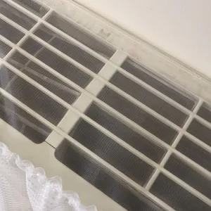 Détail de housse anti-poussière de climatiseur en dentelle avec grille et bordure.