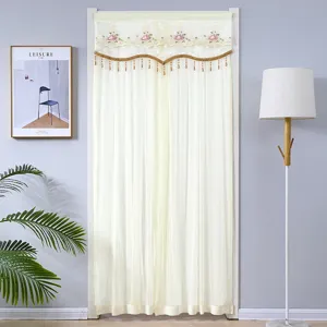Détail du rideau de porte en dentelle avec broderie florale et franges élégantes dans un décor.